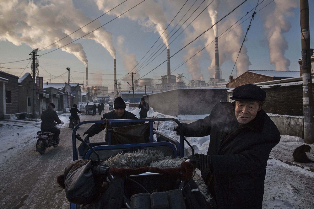 Kevin Frayer, Canada, 2015. Dipendenza dal carbone della Cina Uomini cinesi tirano un triciclo in un quartiere vicino agli impianti di raffineria di carbone a Shanxi in Cina. Courtesy Galleria Carla Sozzani, Milano